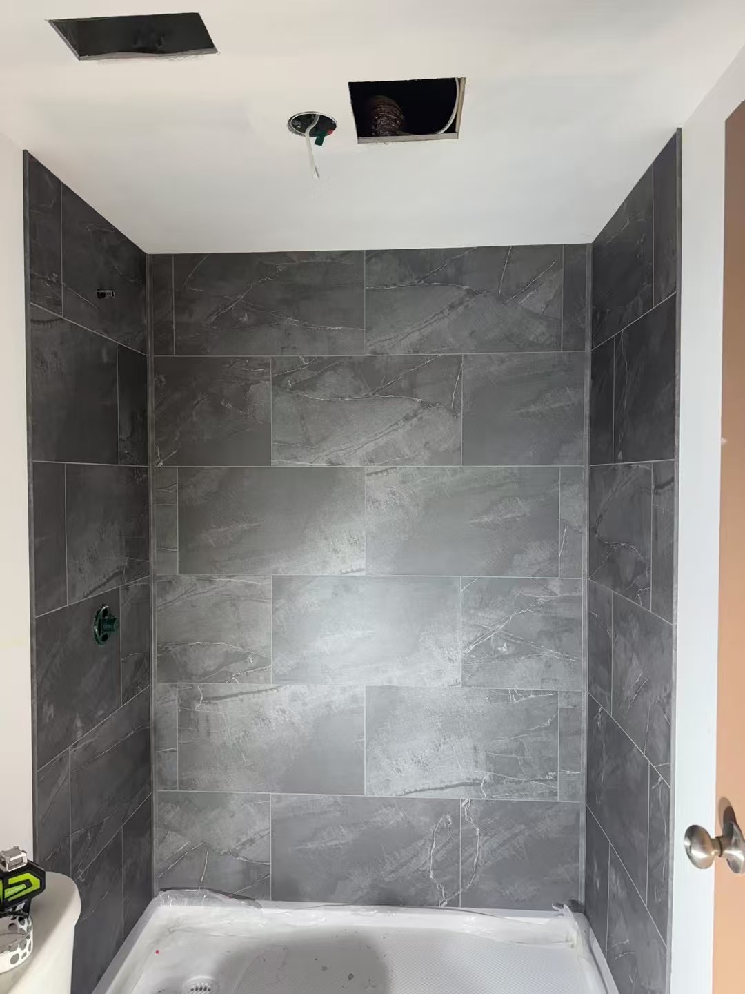 Tiled shower wall during finishing work after waterproofing