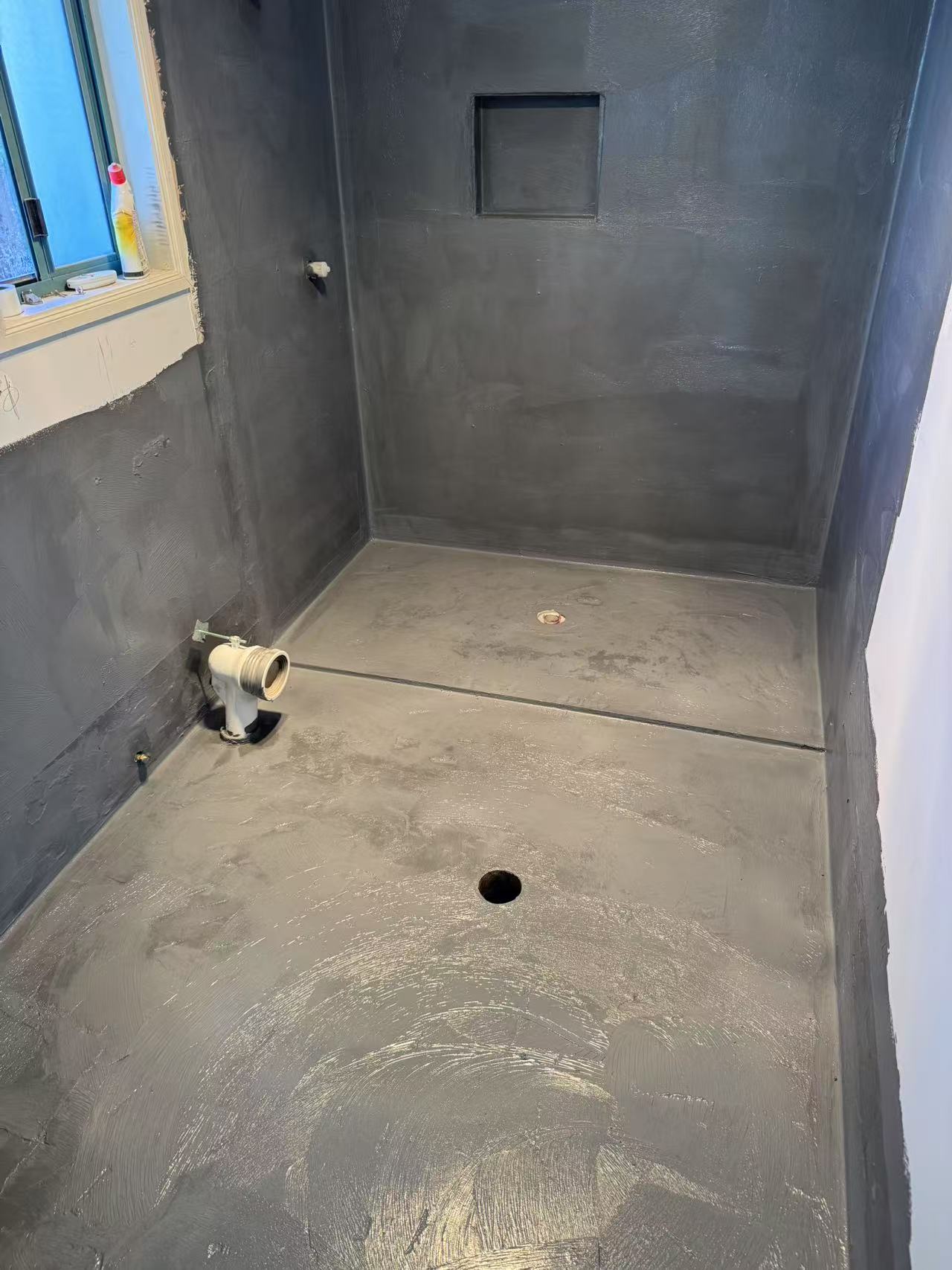 Dark waterproof membrane covering shower walls and bathroom floor
