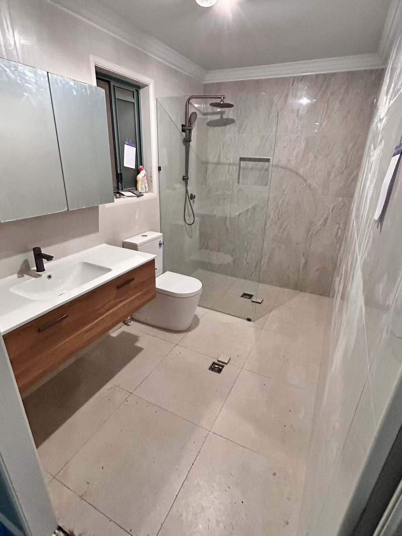 Completed bathroom with shower screen, timber vanity, toilet and tiled floor