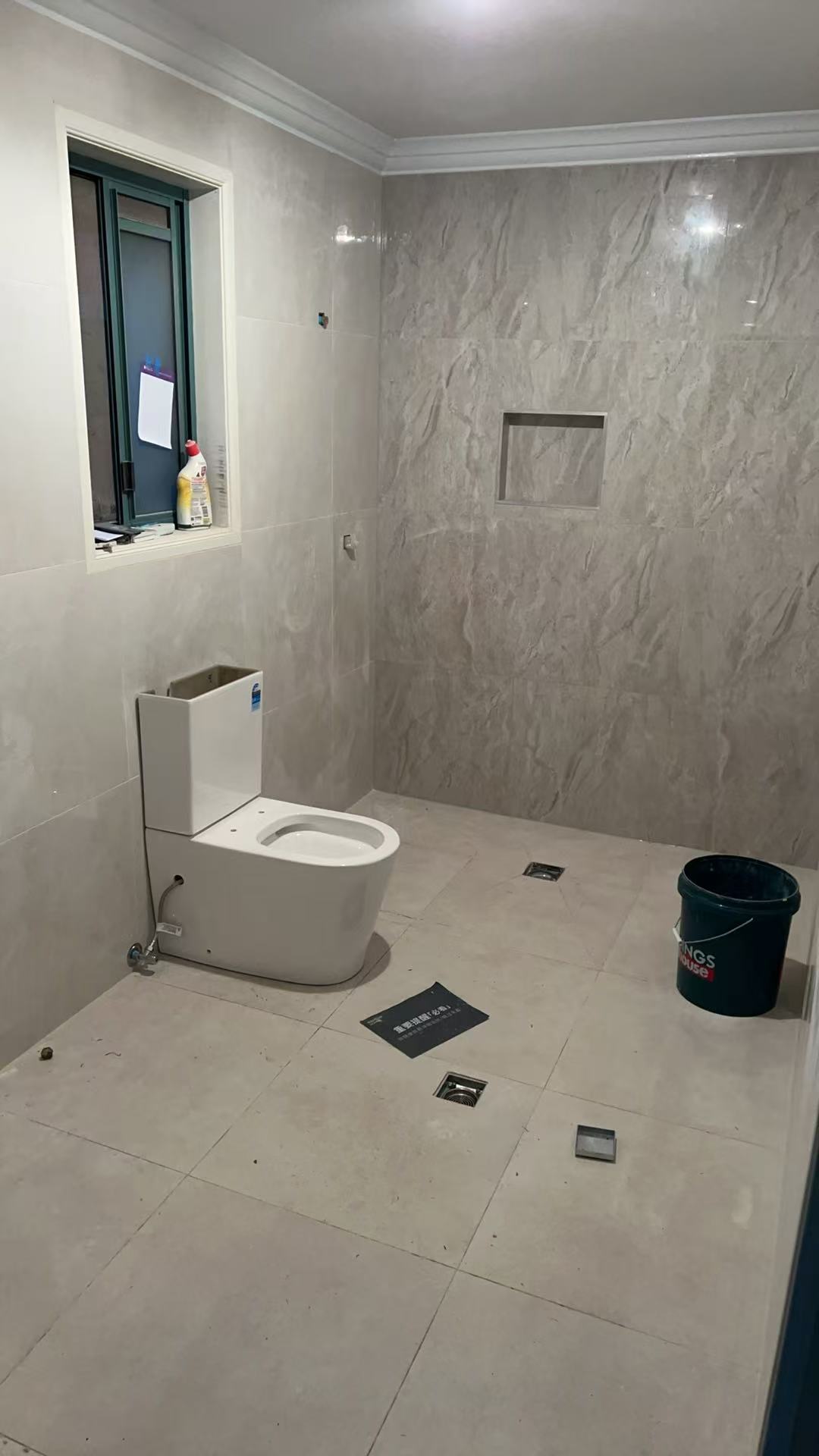 Completed grey tiled shower area with toilet and floor wastes