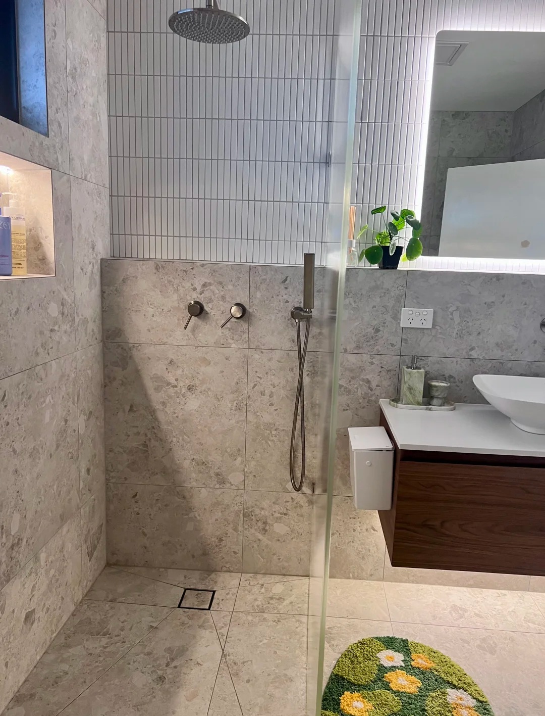 Completed stone-look tiled walk-in shower beside a floating timber vanity