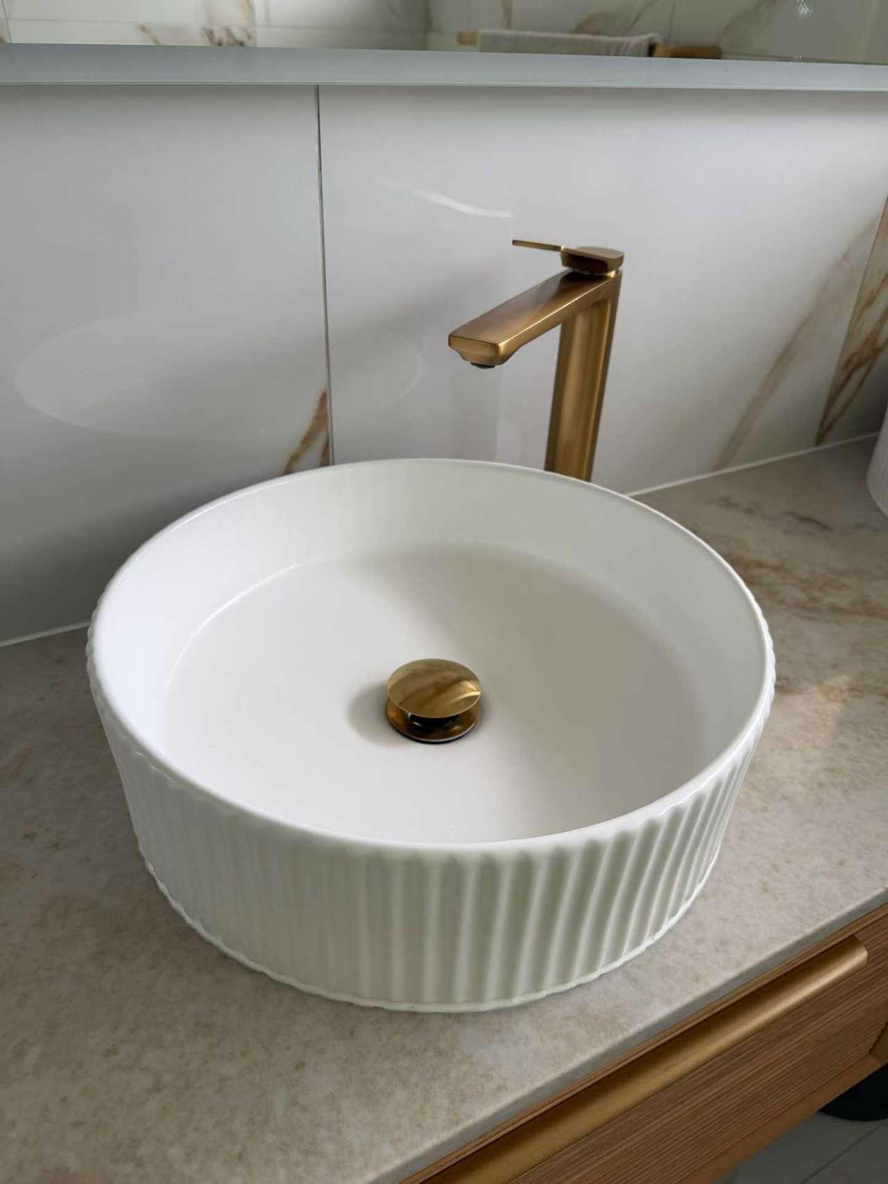Fluted white basin with brushed-gold tap and waste fitting
